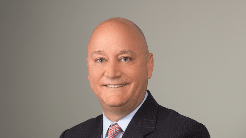 A bald man in a suit and tie posing for a photo.