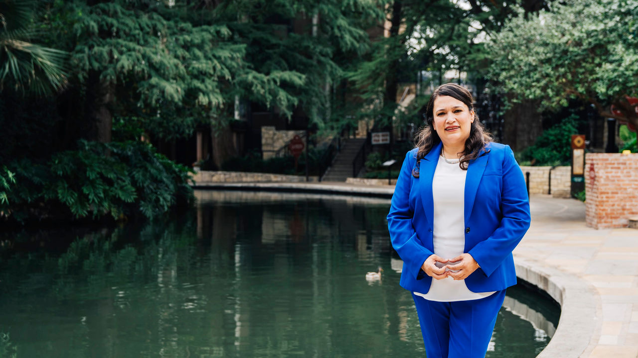 A woman in a blue suit standing next to a pond.