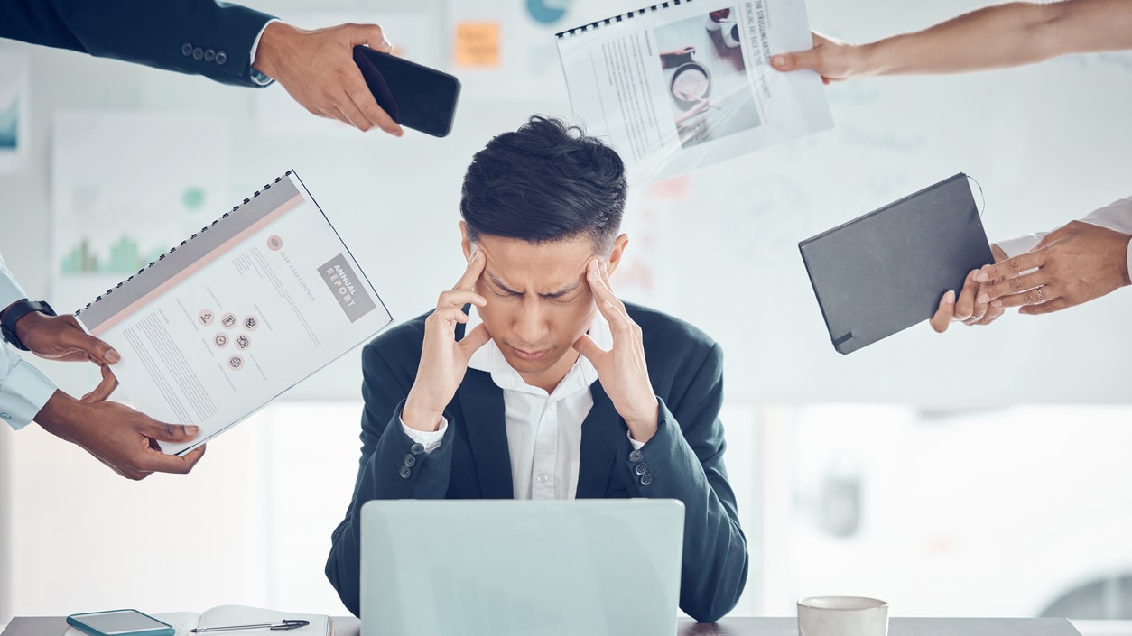 A man in a business suit is holding his head up in front of a group of people.