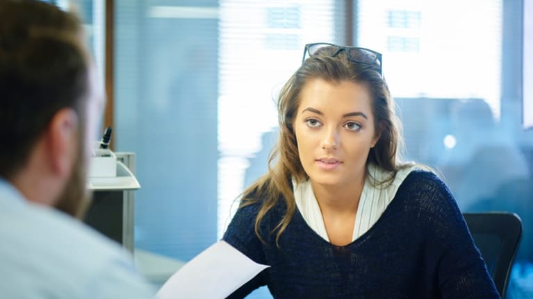 A woman is talking to a man in an office.