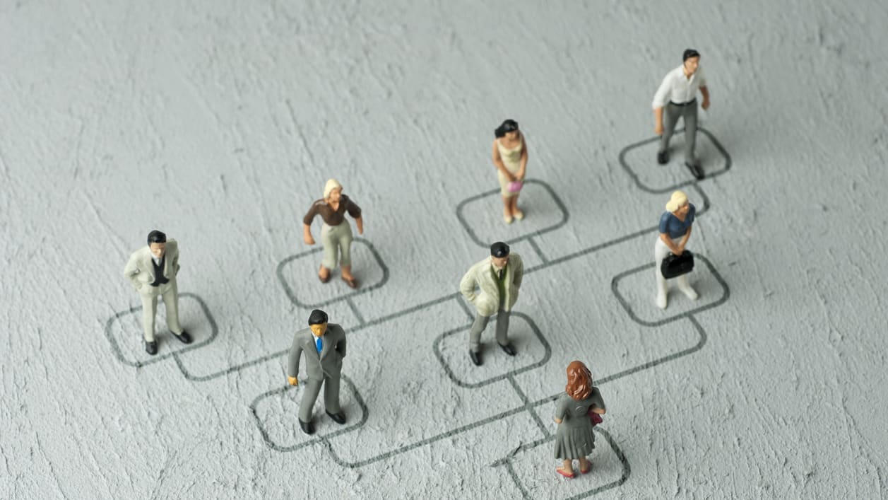 A group of toy people standing on a grey background.