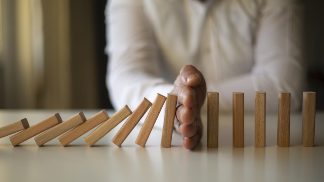 A man is holding a wooden domino on a table.