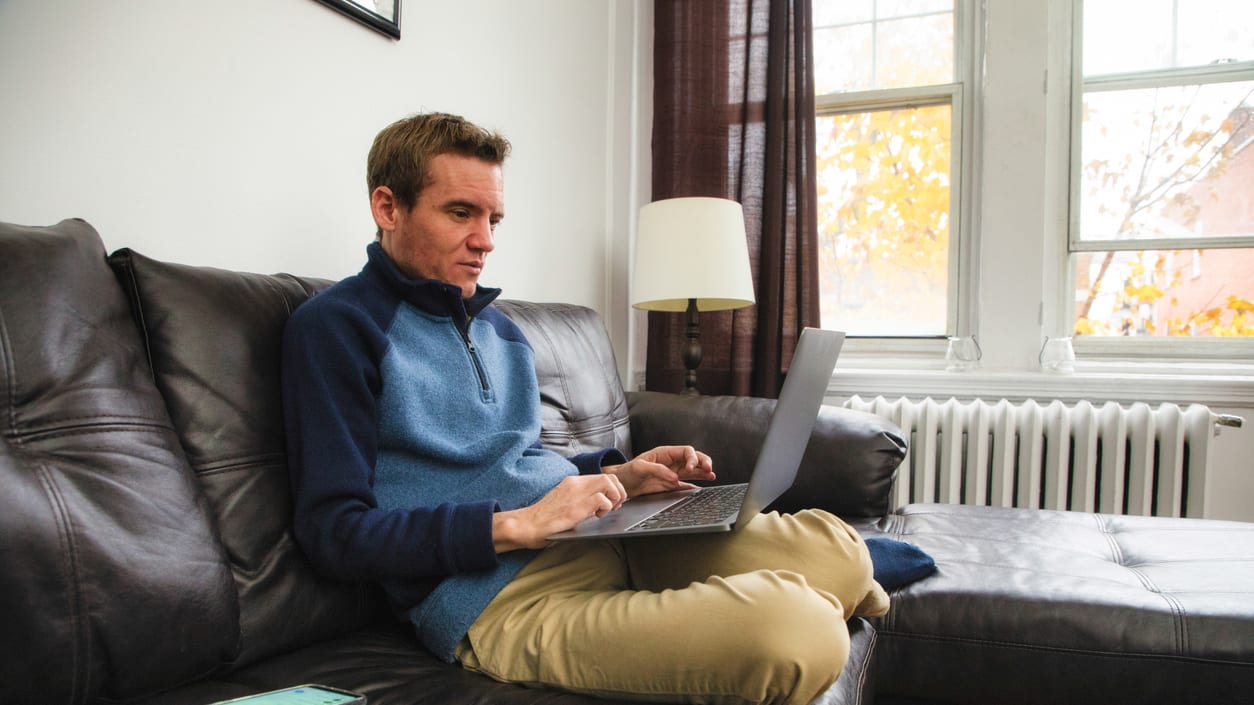 A man sitting on a couch using a laptop.