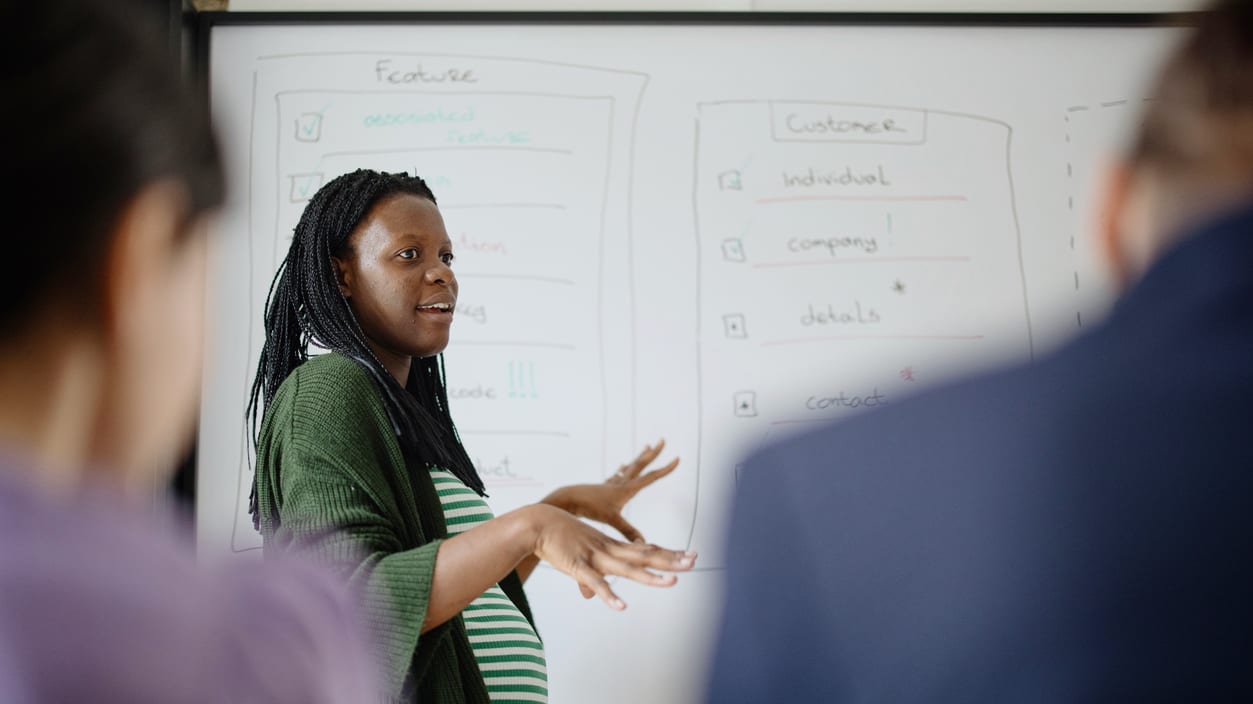 A woman giving a presentation in front of a whiteboard.