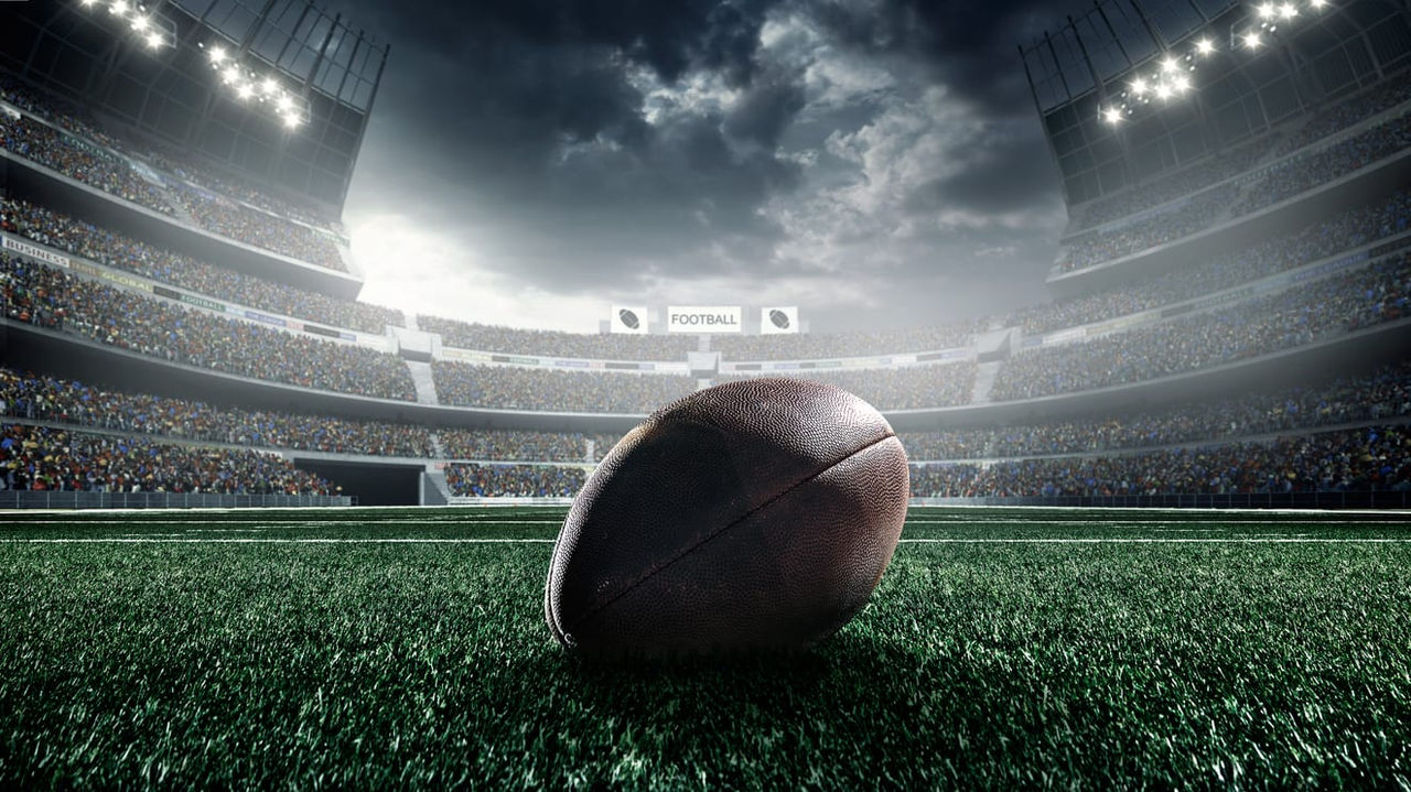A football is sitting on the field of a stadium.