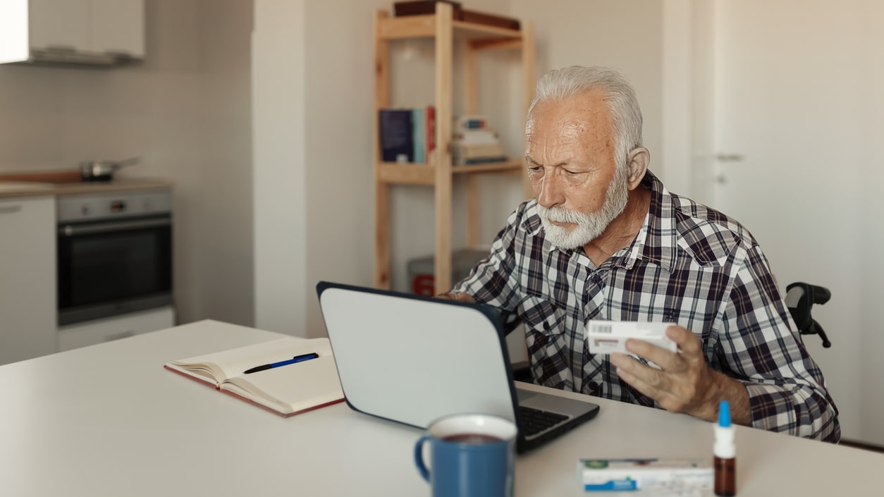 An elderly man using a laptop at home.