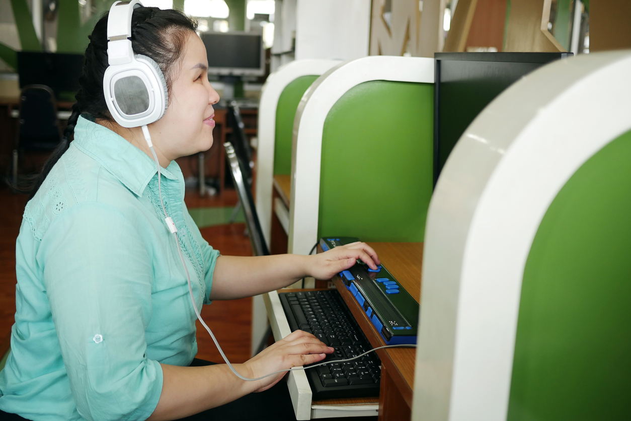 woman with disability wears headphones at computer