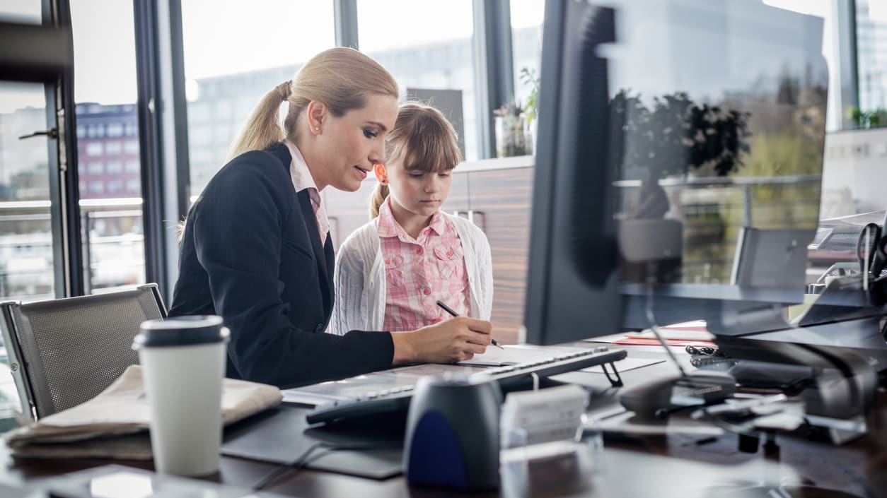 A woman and a child working at a desk in an office.