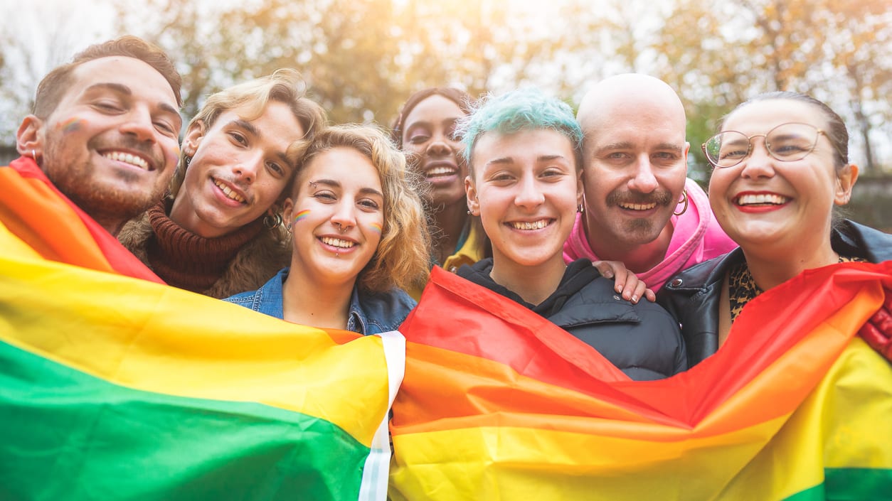 A group of people holding a rainbow flag.