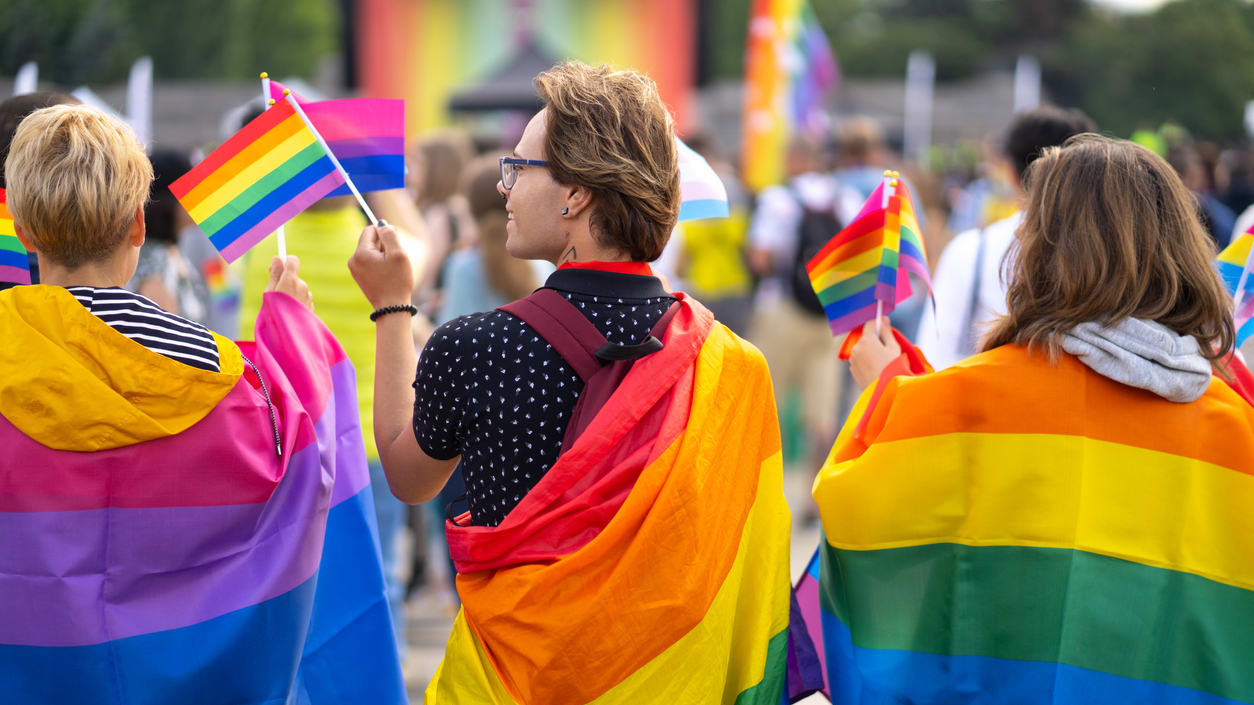 A group of people holding rainbow flags in a parade.