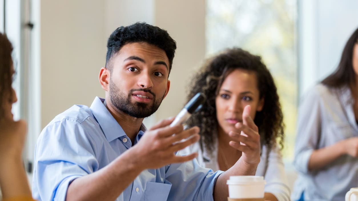 A group of people sitting around a table in a meeting.