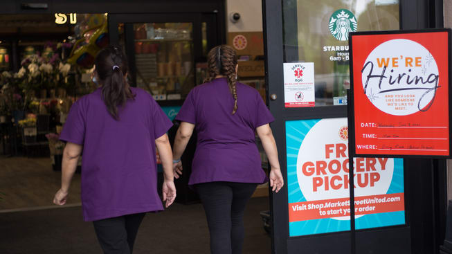 Two grocery store workers walking out of the door.