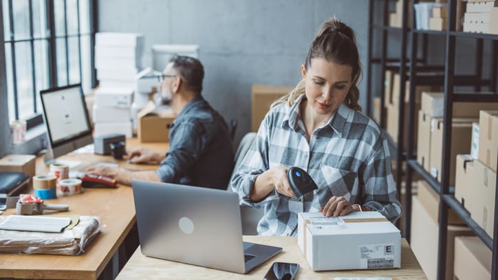 A woman working in an office with a laptop and boxes.