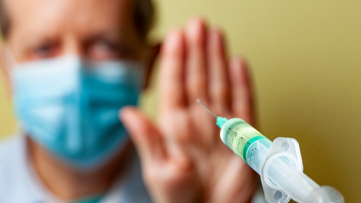 A man in a medical mask holding a syringe.