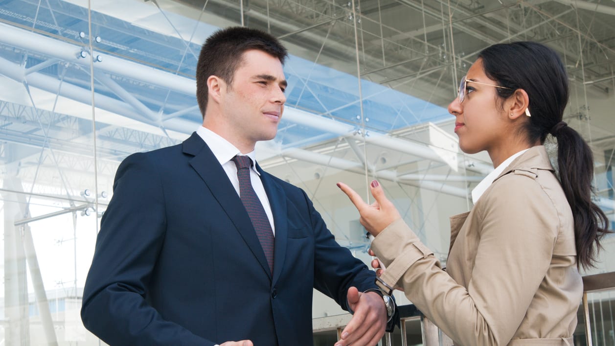 Two business people talking in front of a building.