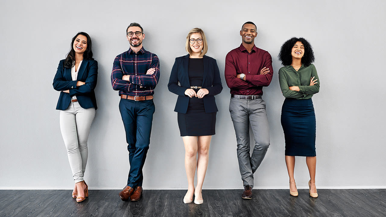 A group of business people standing in front of a gray wall.