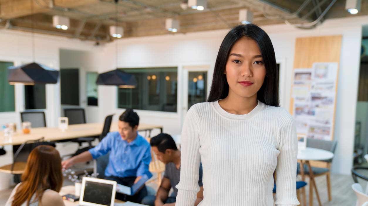 Woman standing in an office with people around her.