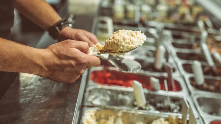 A man is scooping ice cream from a tray.