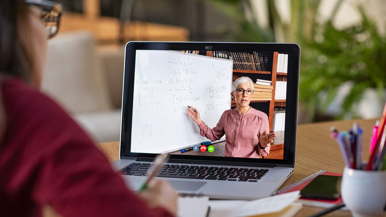 A woman is using a laptop to draw on a whiteboard.