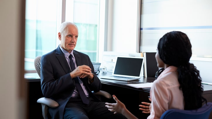 A businessman talking to a woman in an office.