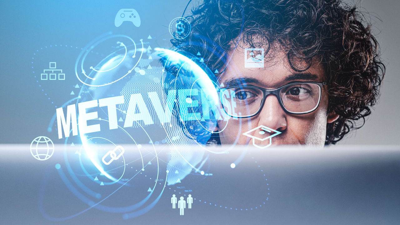 A man is looking at a computer screen with the word metaverse on it.