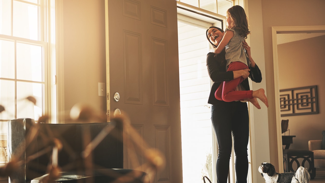 A woman and her daughter standing in front of a door.