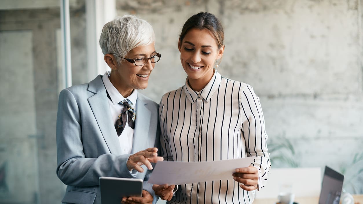 Two business women looking at a document in an office.