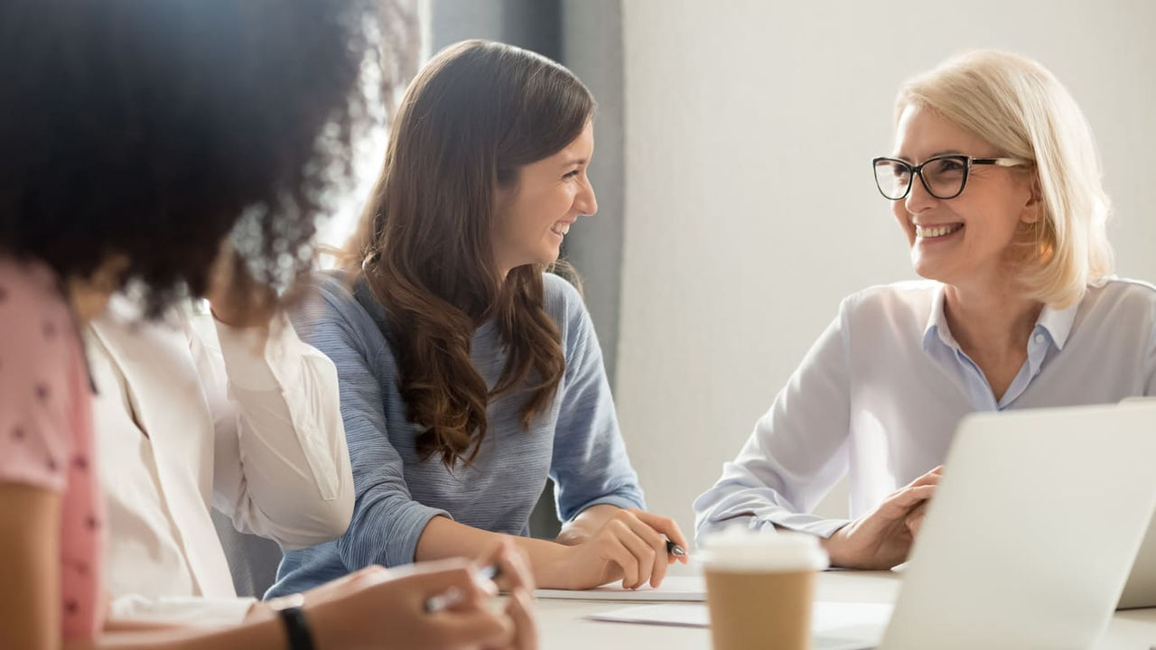 A group of people sitting around a table talking to each other.