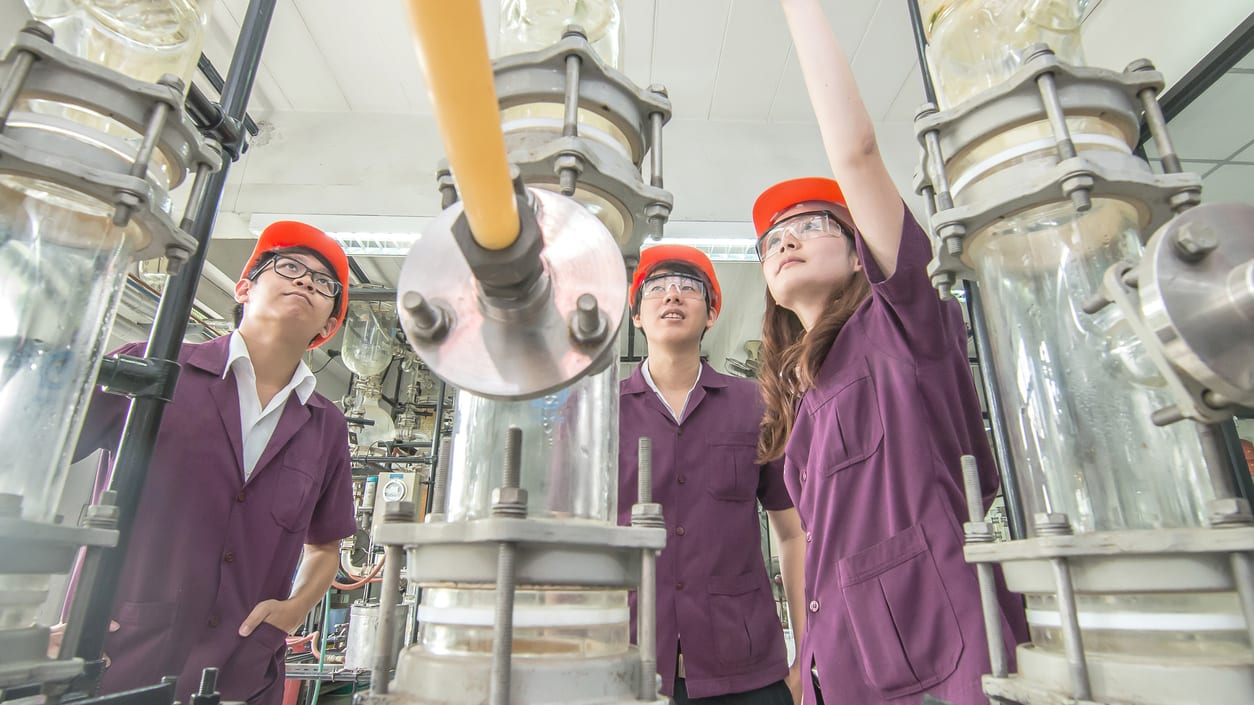 A group of students looking at a machine in a factory.