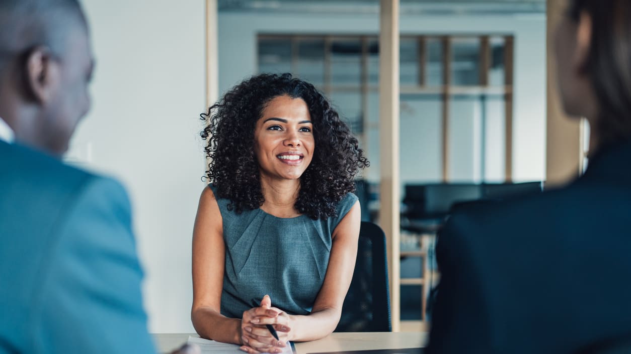 A woman is talking to an interviewer in an office.