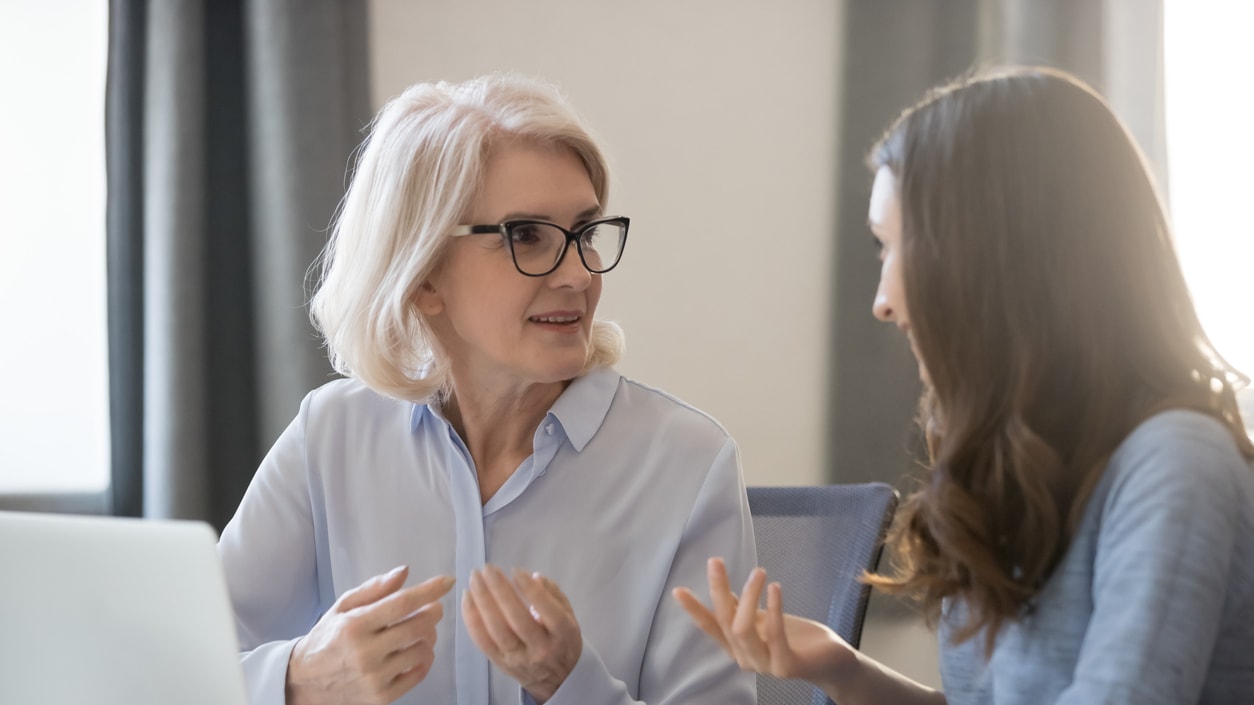 Two women talking in front of a laptop.