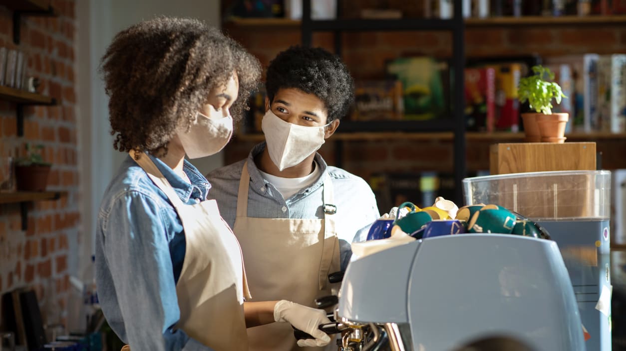 Two women in face masks working at a coffee shop.