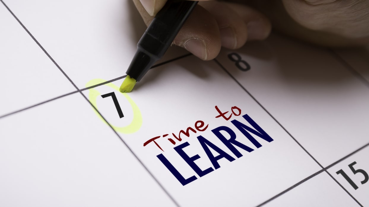 A person writing the word time to learn on a calendar.