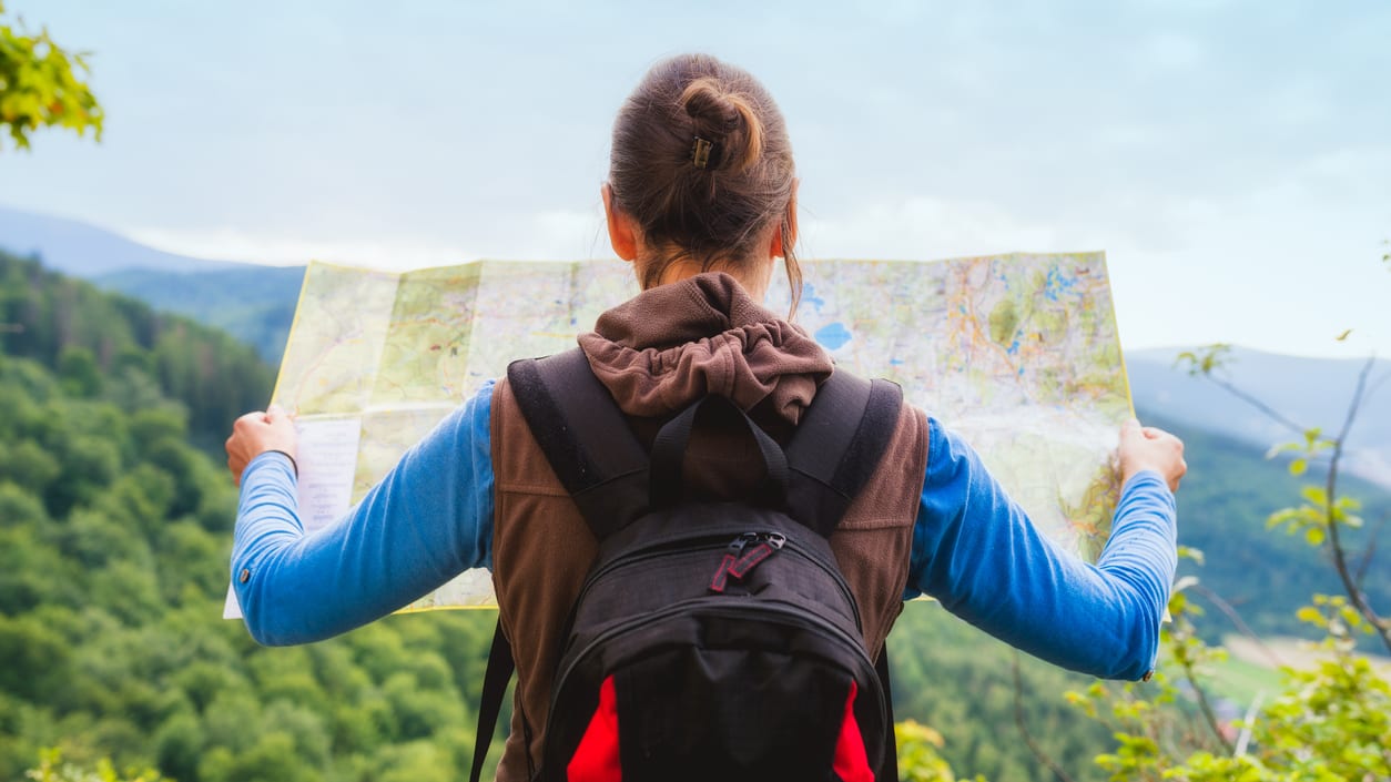 A woman looking at a map while hiking in the mountains.