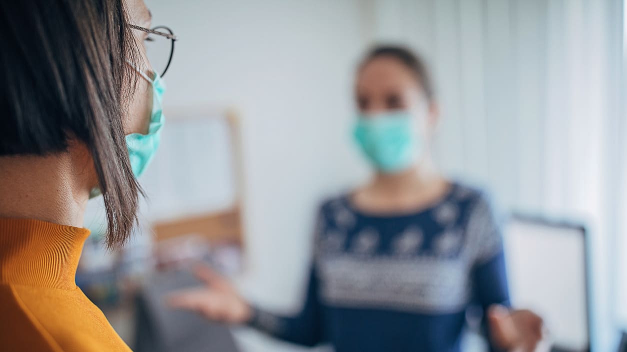 Two women wearing face masks in an office.