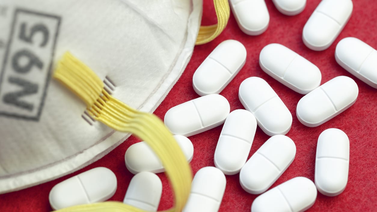 A white mask with pills on a red background.