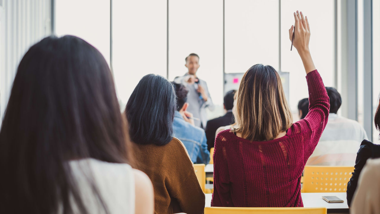 A group of people in a classroom raising their hands in the air.