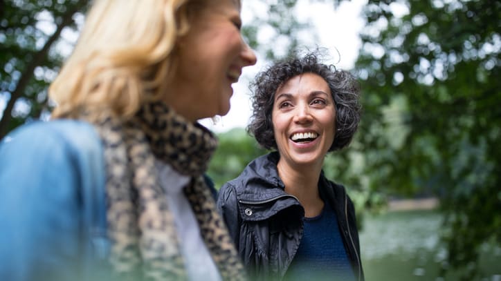 Two women talking near a pond.