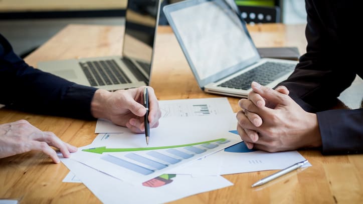 Two business people sitting at a table and looking at graphs.