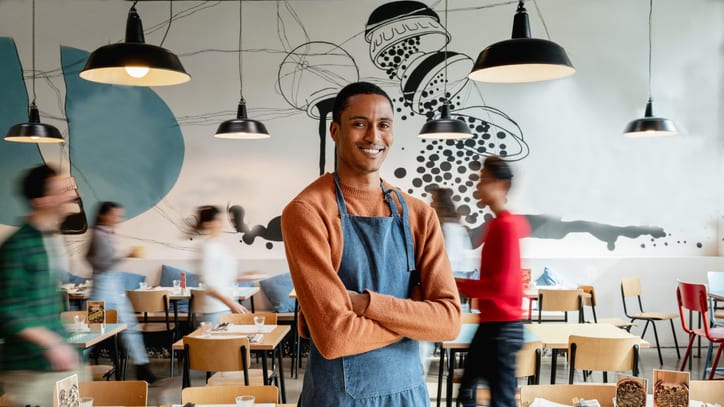 A woman in an apron standing in a restaurant.