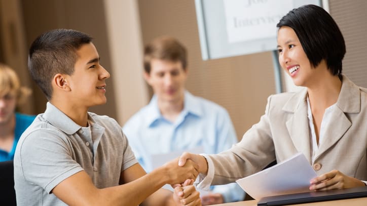 A woman shaking hands with a man at a desk.