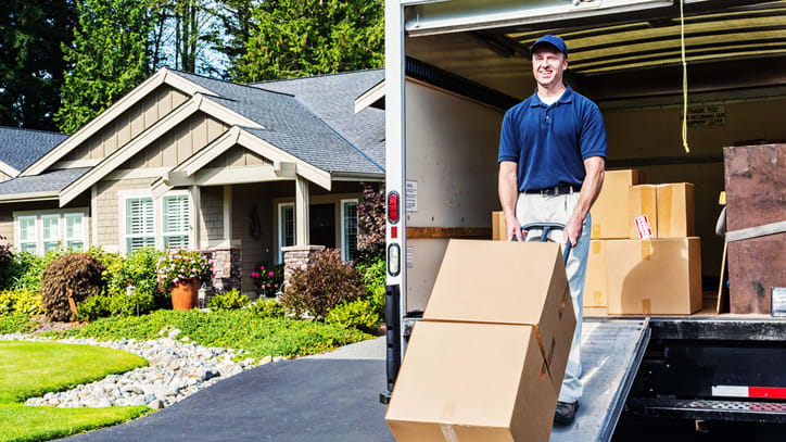 A man loading boxes into a moving truck in front of a house.