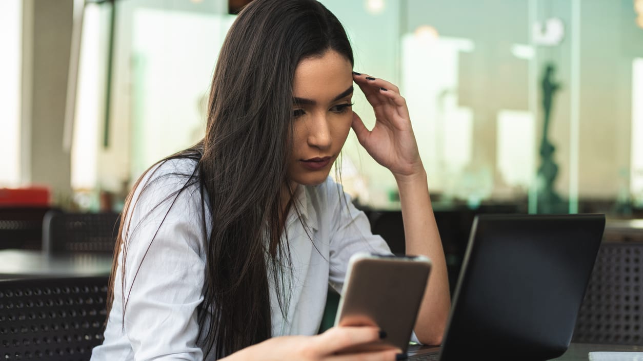 A woman looking at her phone while sitting at a table.