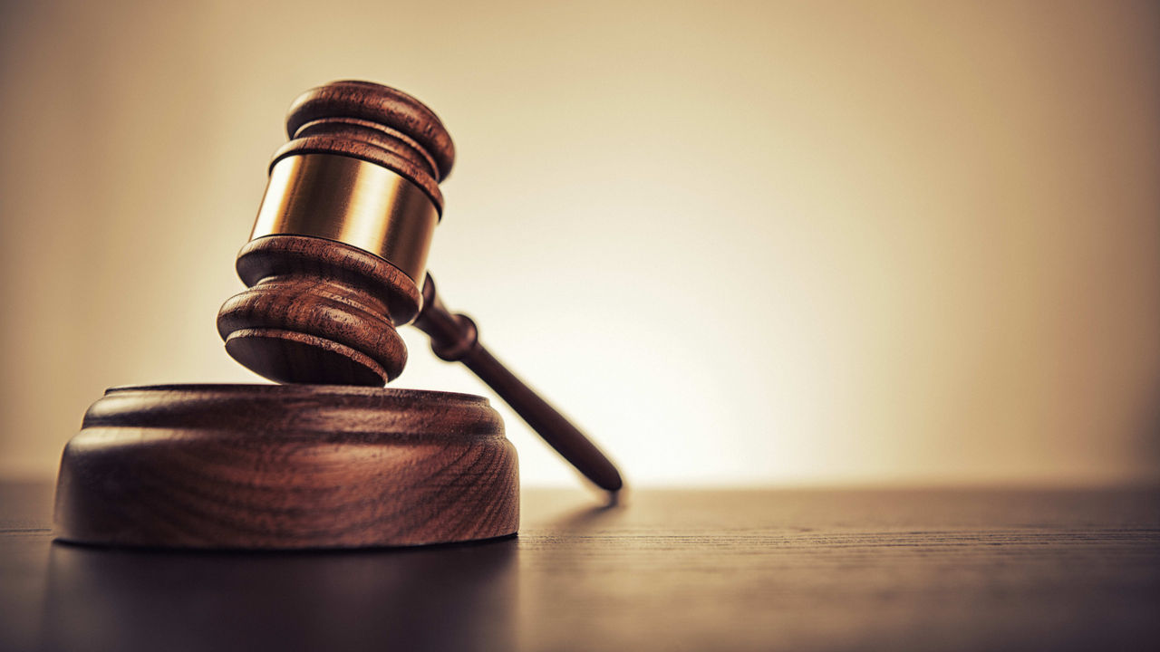 A wooden gavel sits on top of a wooden table.