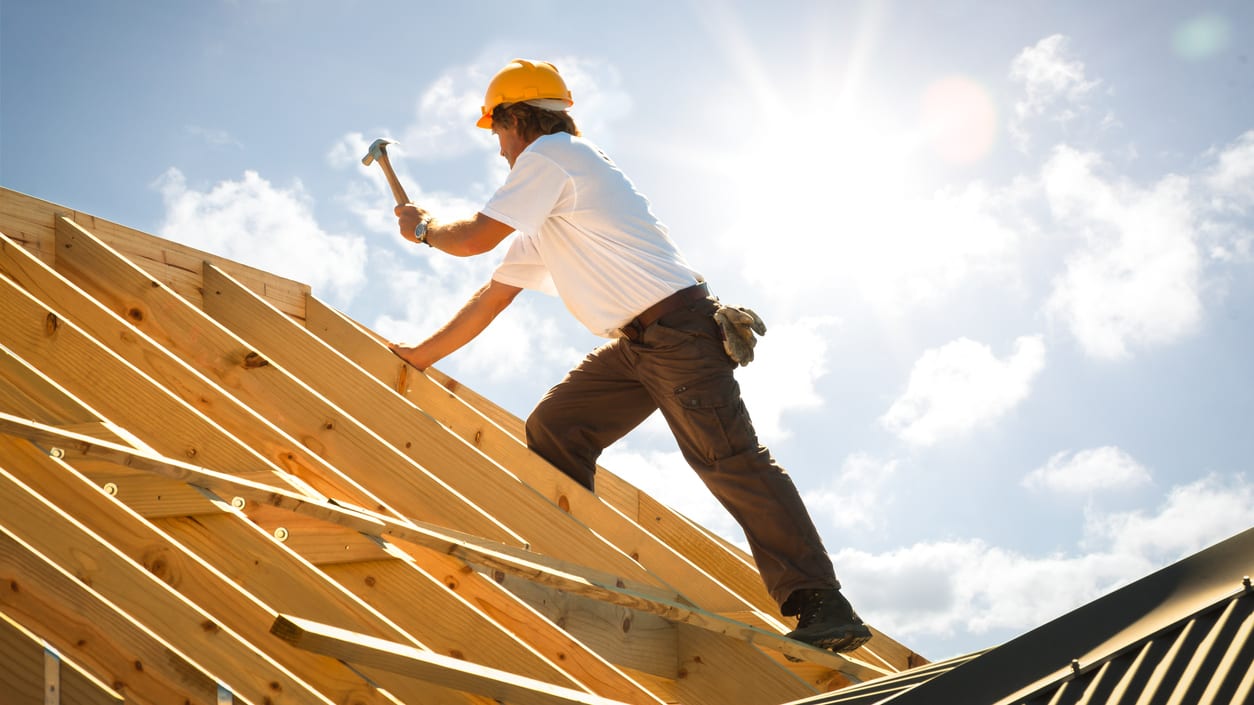 A construction worker is working on a roof.