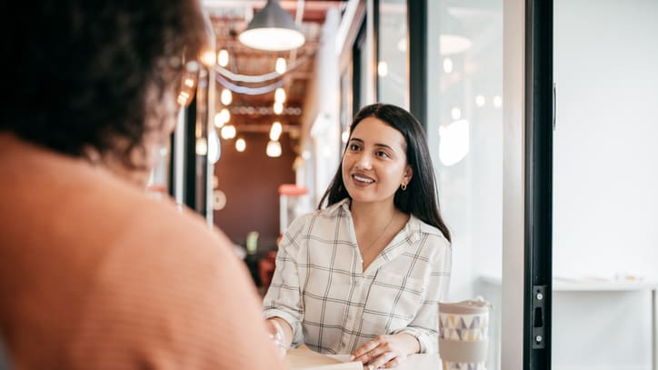 Two women talking at a table in an office.