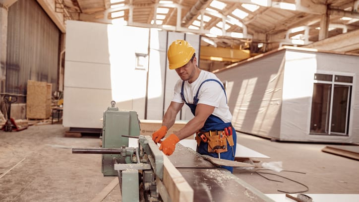 A worker is working on a planer in a factory.