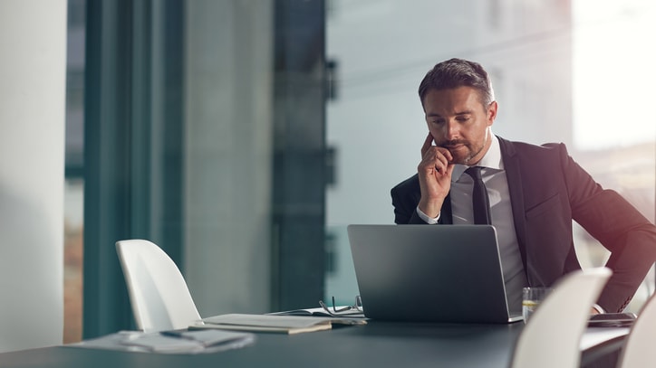 A businessman talking on the phone while sitting at a desk.