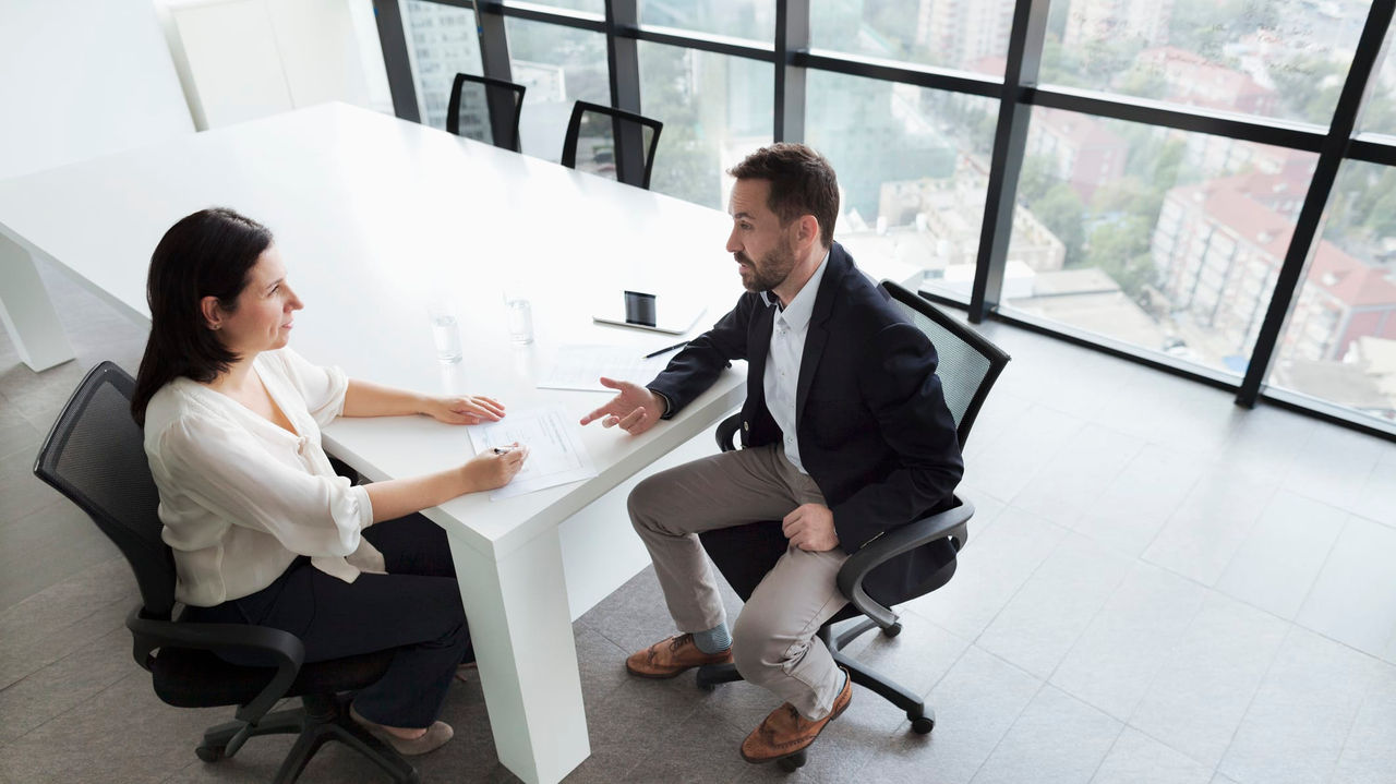 Two business people sitting at a table in an office.