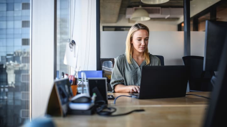 A woman working on a laptop in an office.